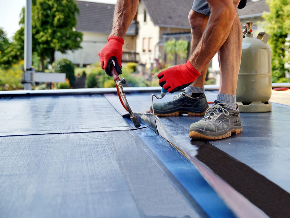 A roofer torching down a new felt flat roof
